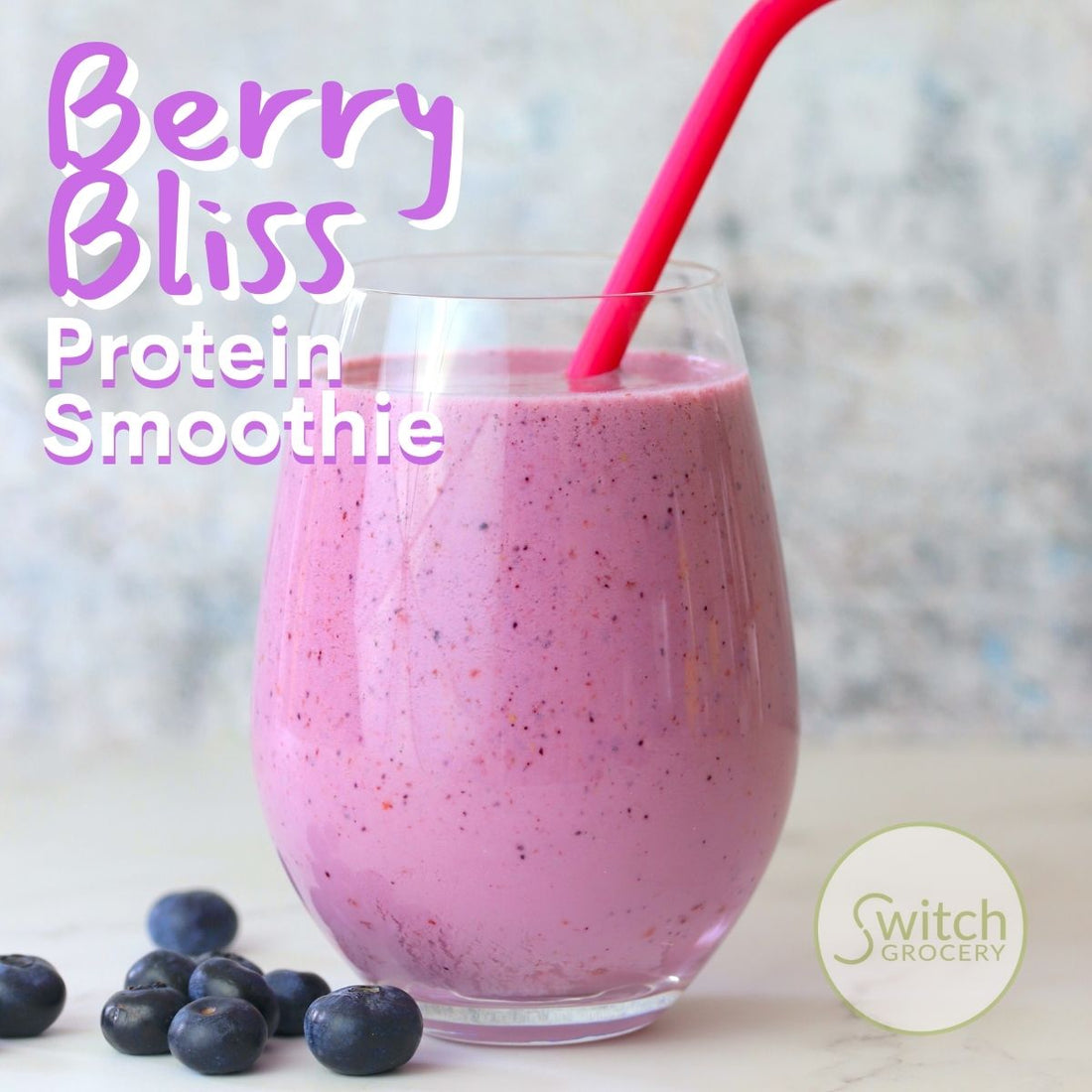 Low Carb berry Bliss Protein Smoothie in a glass with a straw next to blueberries.